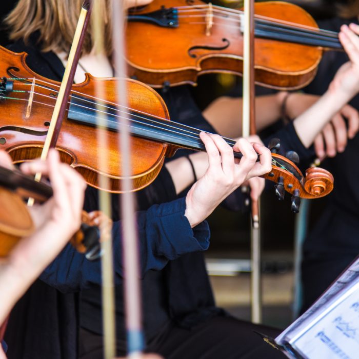 Musikere i Symphony Sounds spiller på fiolin under en liveopptreden.